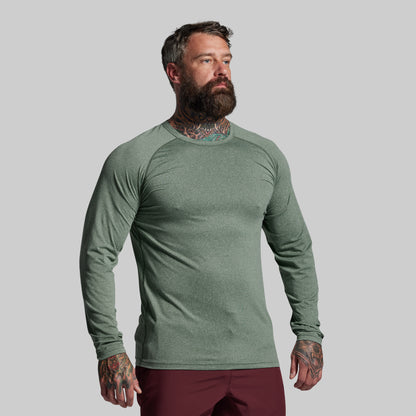 Man wearing a green long-sleeve shirt against a gray background
