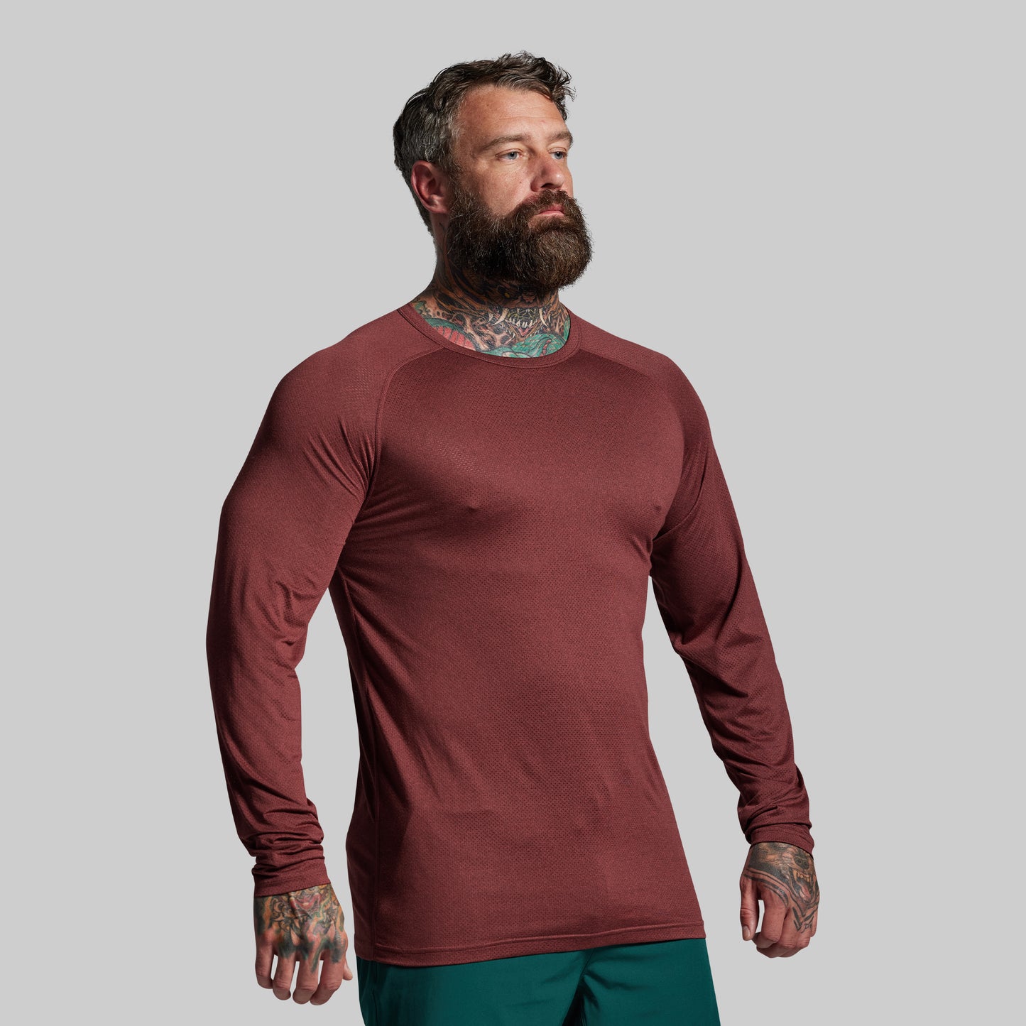 Man wearing a maroon long-sleeve shirt against a gray background