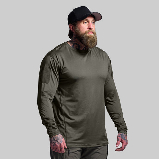 Man wearing a green long-sleeve shirt and black cap on a gray background