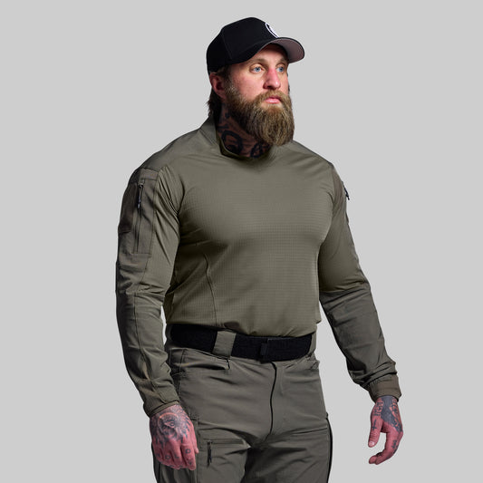 Man wearing a green tactical outfit with a cap on a gray background