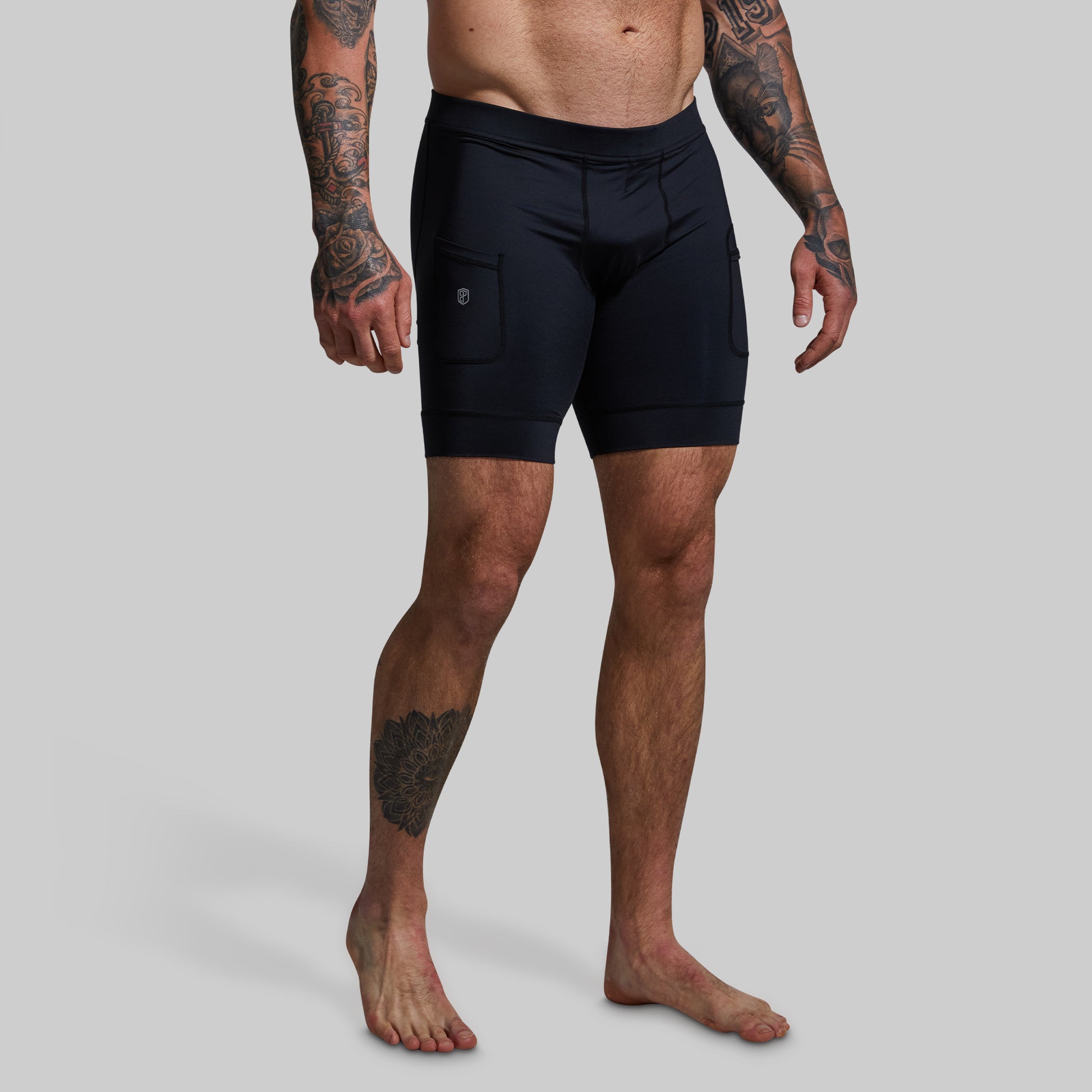 Man wearing black athletic shorts on a gray background