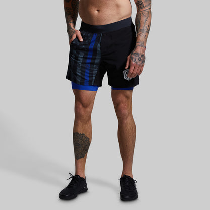 Person wearing black athletic shorts with blue accents on a gray background