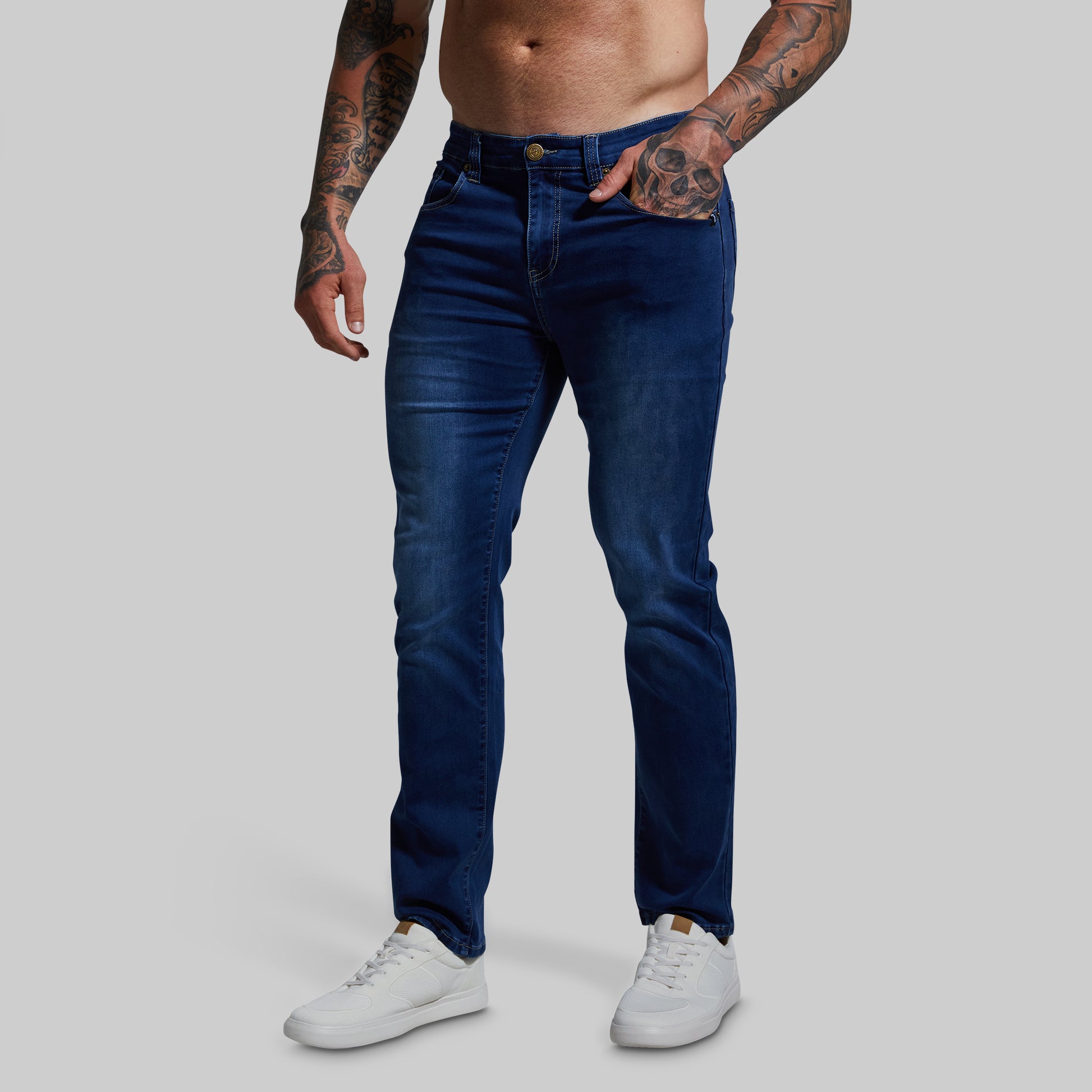 Person wearing blue jeans and white sneakers on a plain background