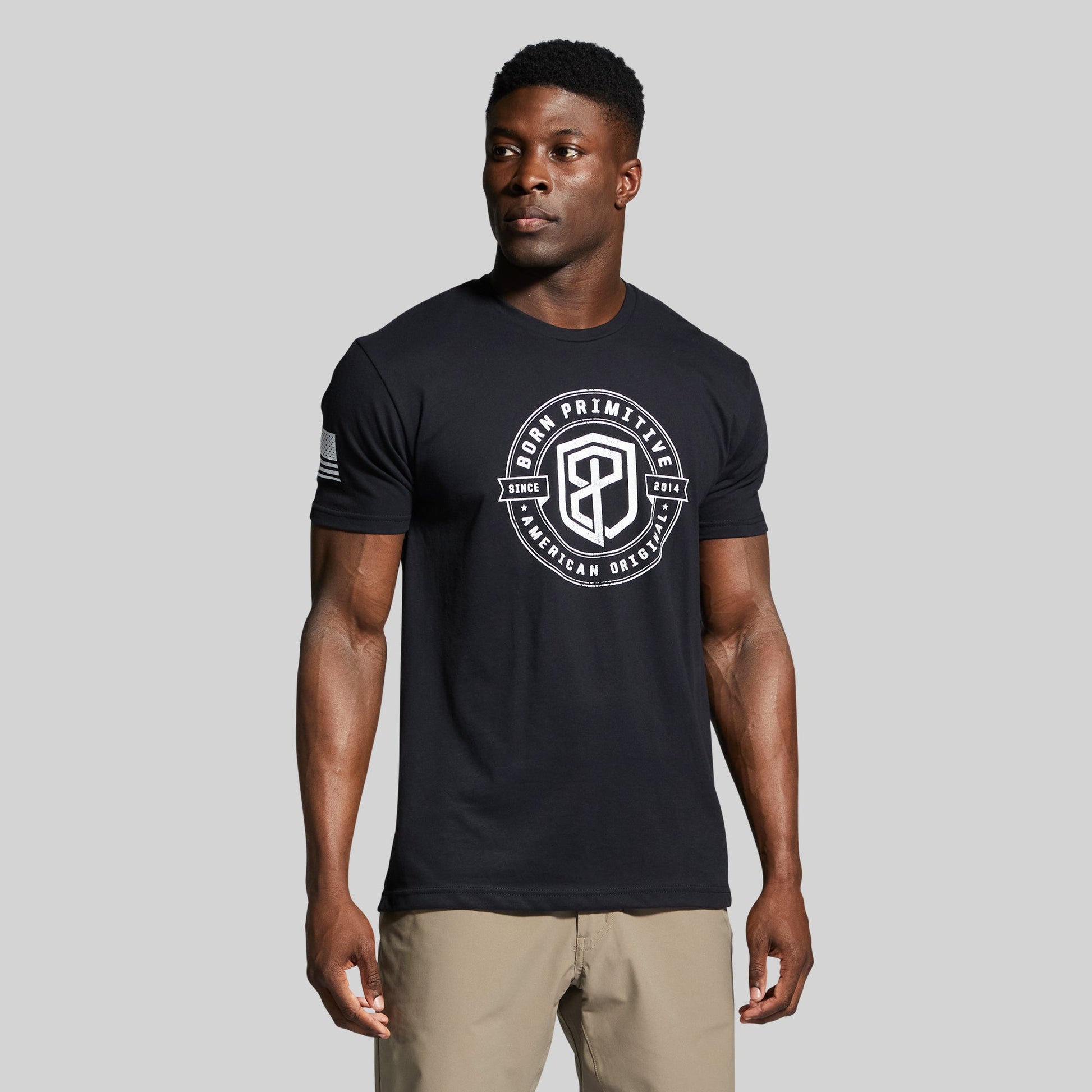 Man wearing a black t-shirt with a logo on a gray background