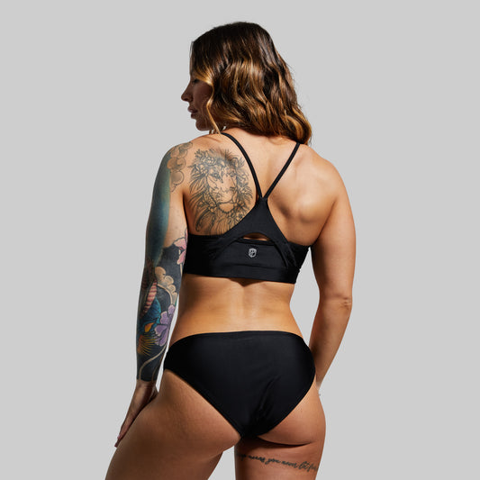 Person wearing a black bikini against a plain background