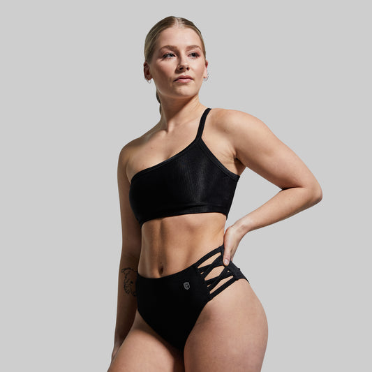 Woman wearing a black bikini against a plain background