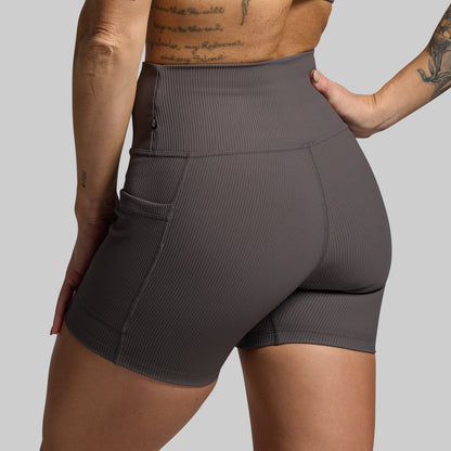 Person wearing dark gray athletic shorts on a plain background
