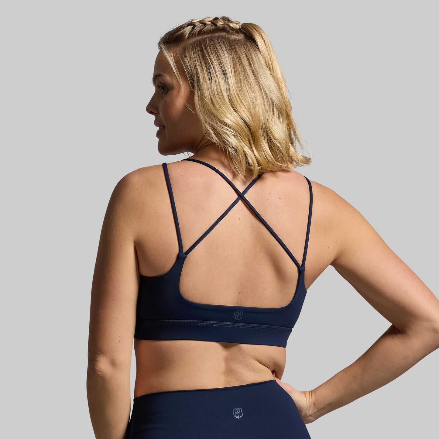 Woman wearing a navy blue sports bra and leggings on a gray background