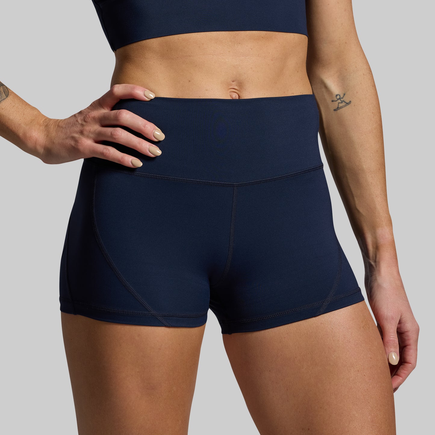 Person wearing navy blue athletic shorts on a gray background