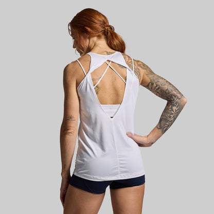 Woman wearing a white tank top with criss-cross back design on a gray background