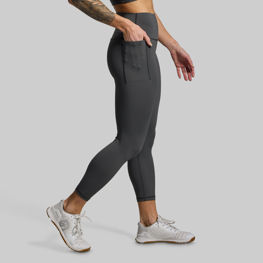 Person wearing dark gray leggings on a light gray background