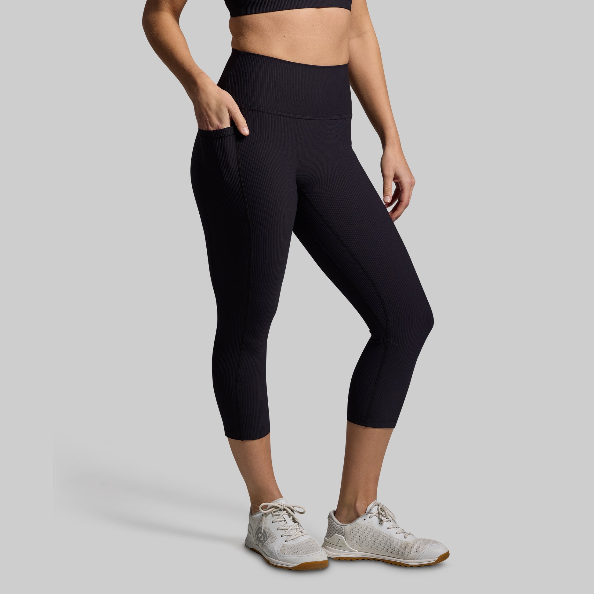 Person wearing black leggings and white sneakers on a gray background