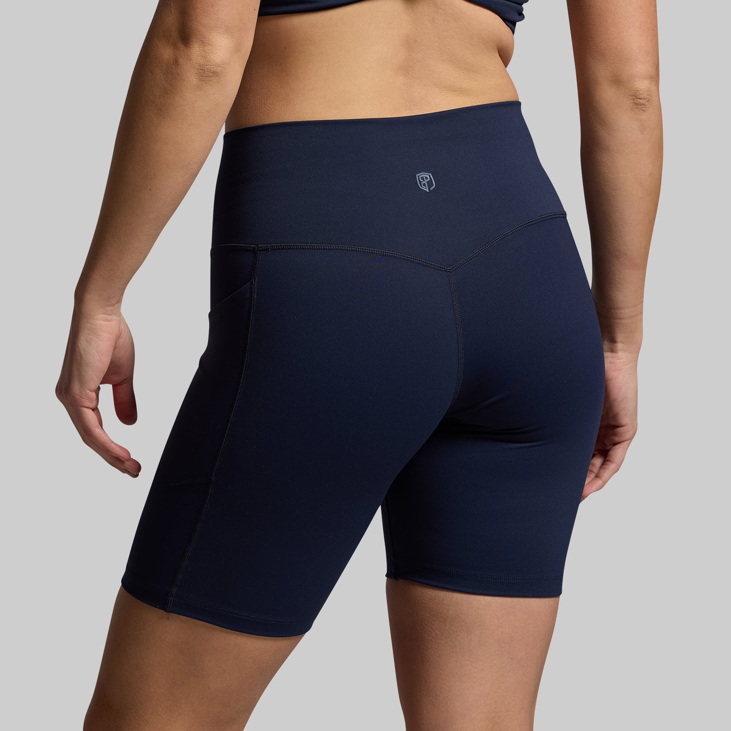 Navy blue athletic shorts worn by a person on a gray background