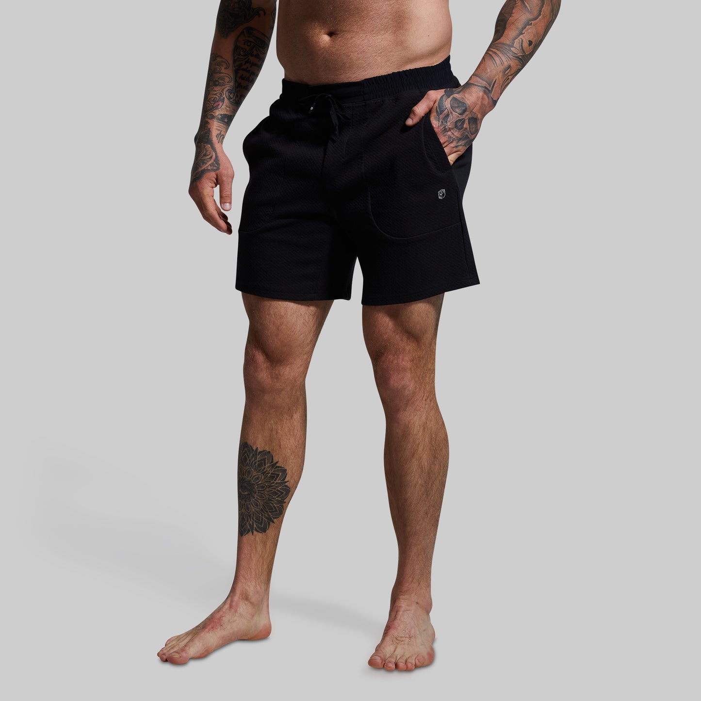 Person wearing black shorts on a plain background