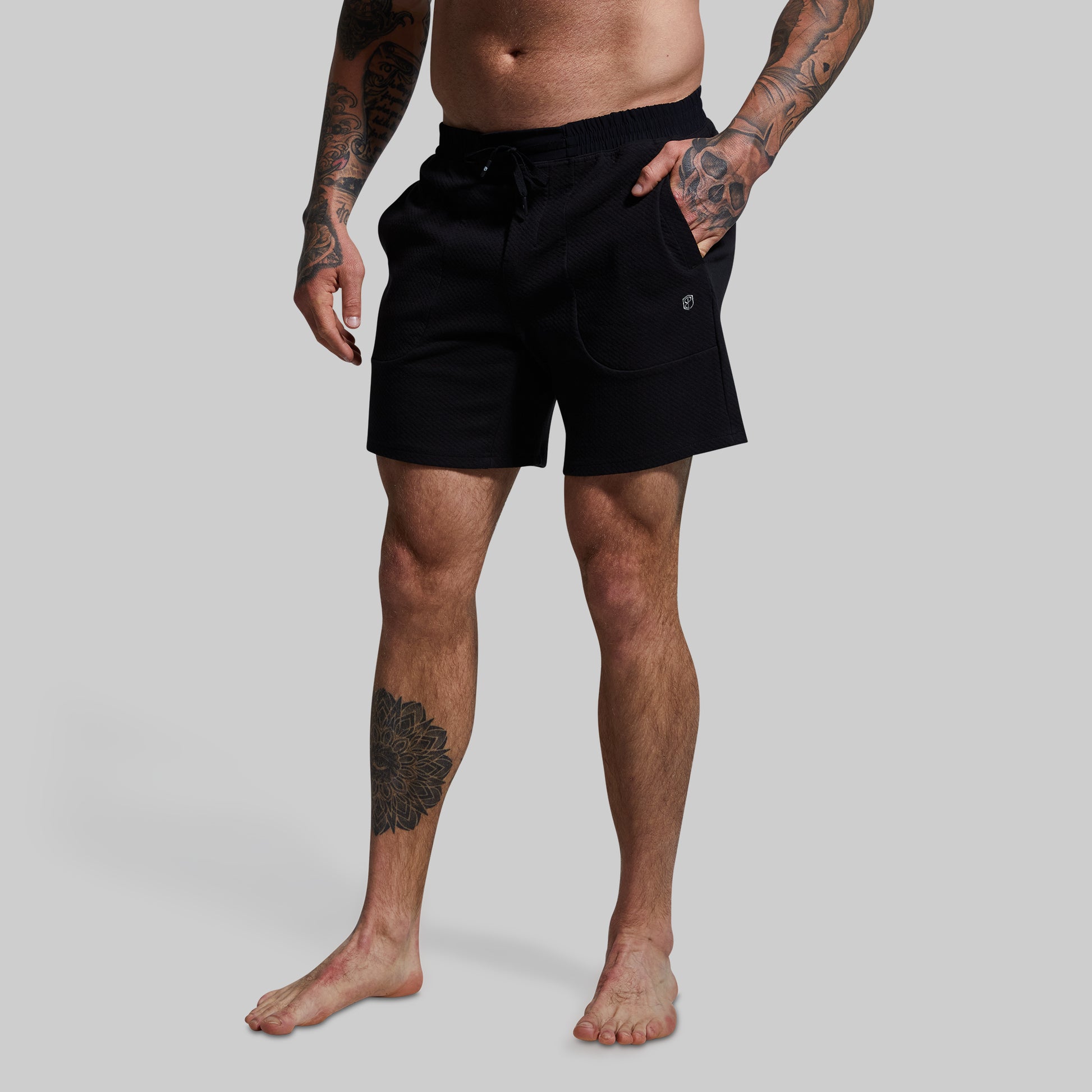 Person wearing black shorts on a plain background
