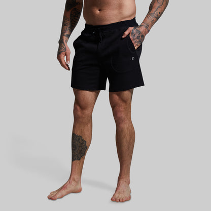 Person wearing black shorts on a plain background