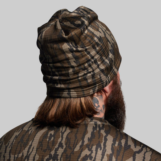 Person wearing a camouflage-patterned beanie and jacket on a plain background
