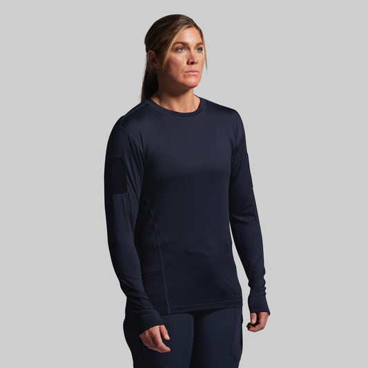 Woman wearing a navy long-sleeve tactical shirt on a gray background