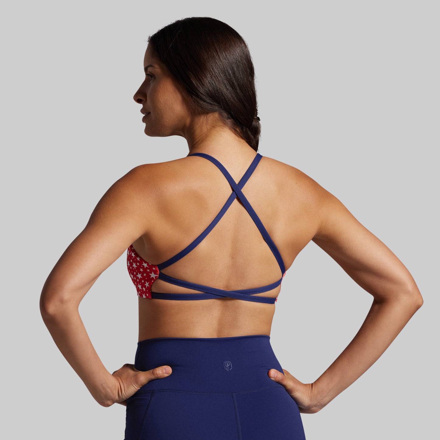 Woman wearing a blue sports bra and leggings on a gray background