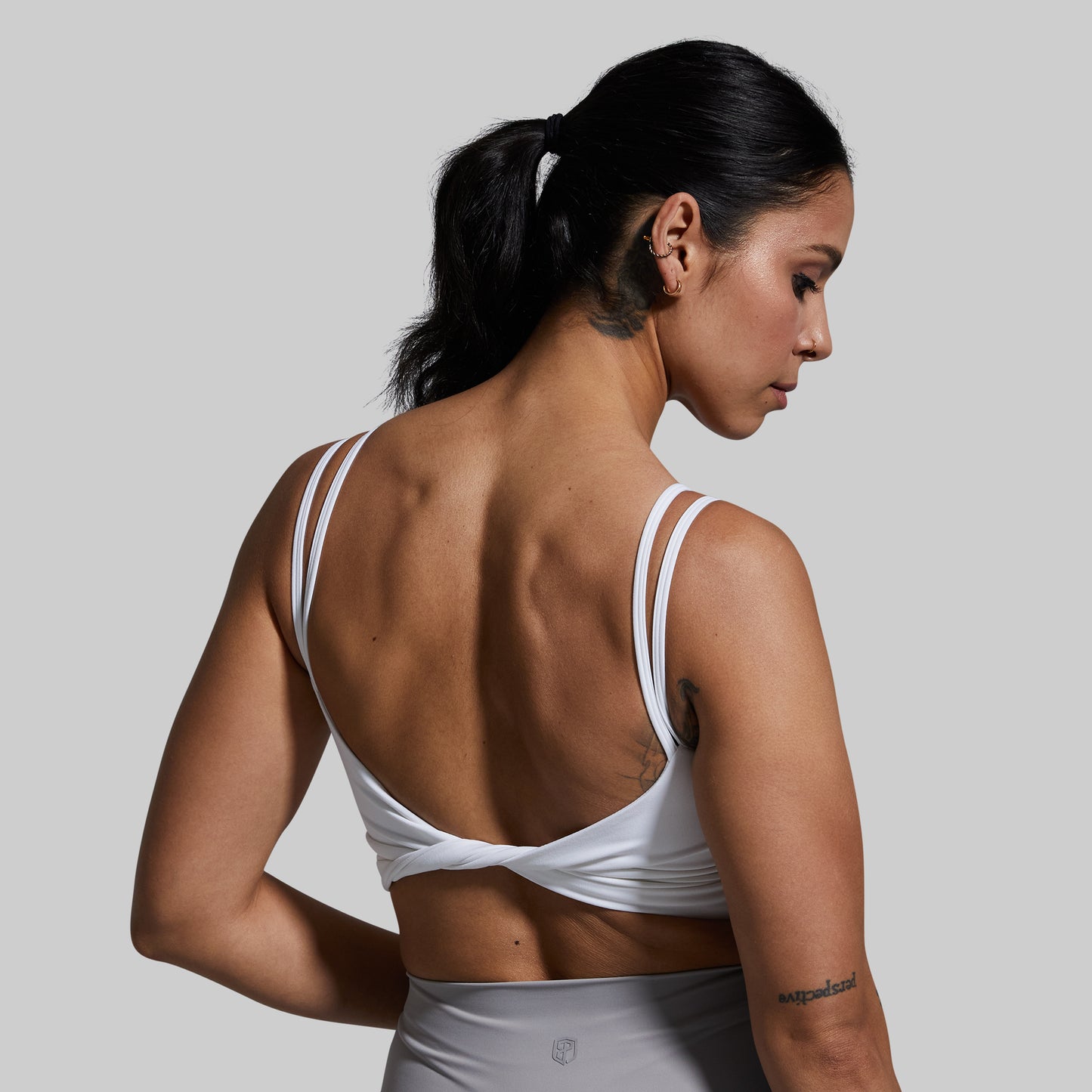 Woman wearing a white sports bra against a plain background