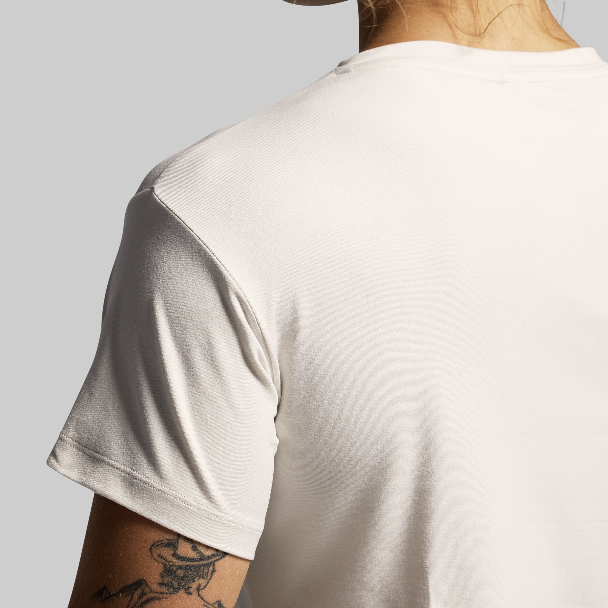 Person wearing a beige t-shirt with a plain background