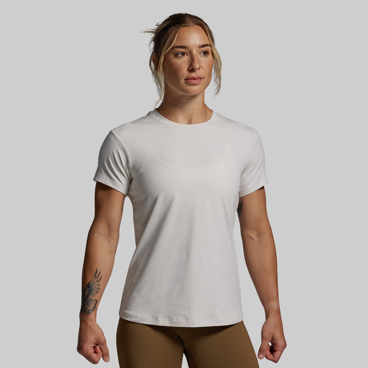 Woman wearing a plain white t-shirt against a gray background