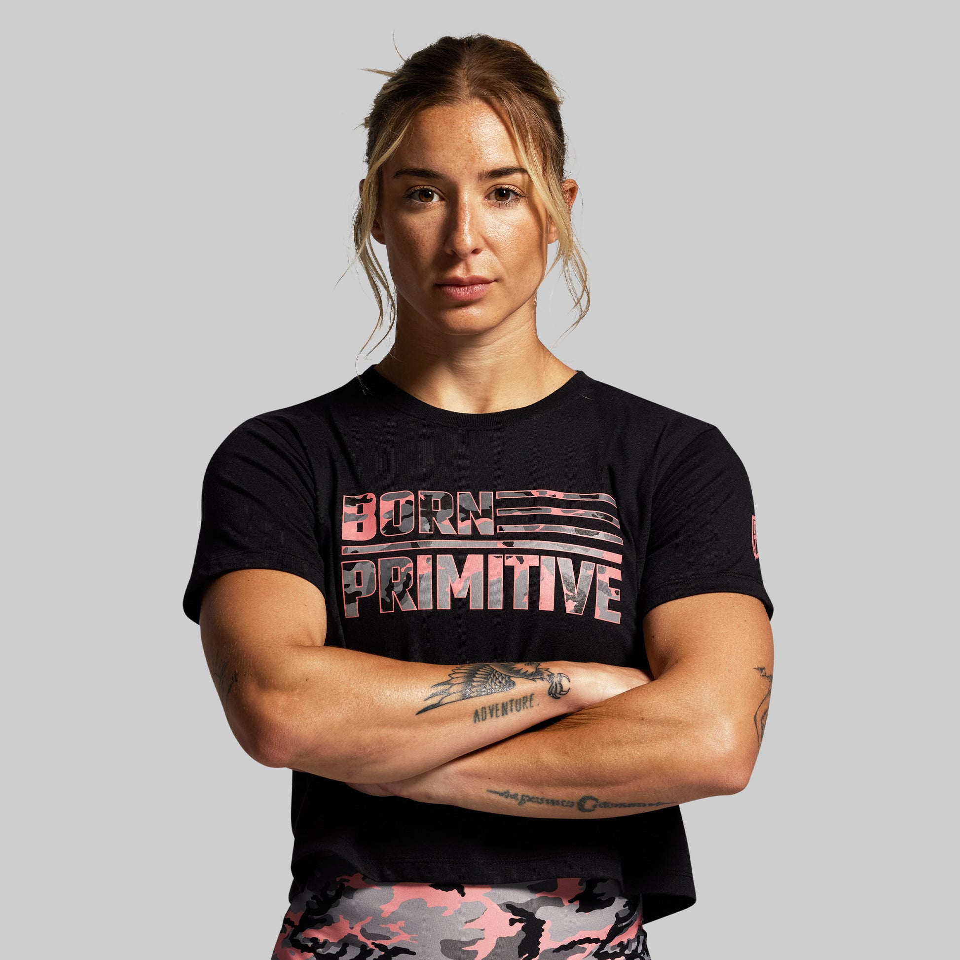 Person wearing a black t-shirt with 'Born Primitive' design on a gray background