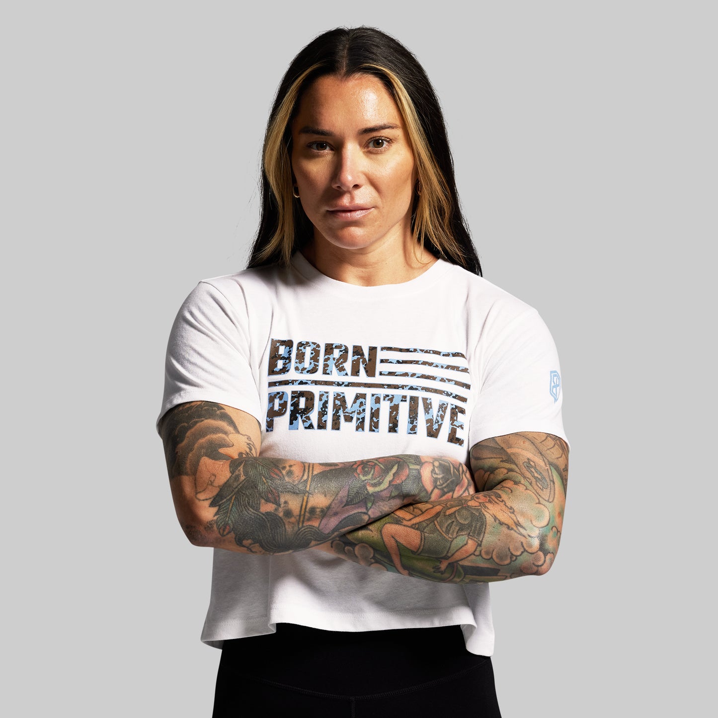 Person wearing a white t-shirt with 'Born Primitive' text on a gray background