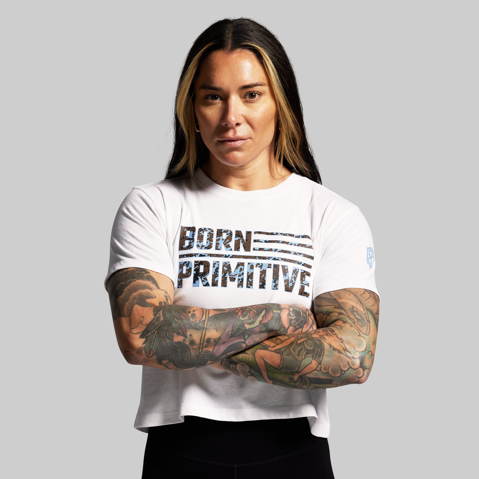Person wearing a white t-shirt with 'Born Primitive' text on a gray background