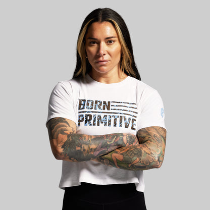 Person wearing a white t-shirt with 'Born Primitive' text on a gray background
