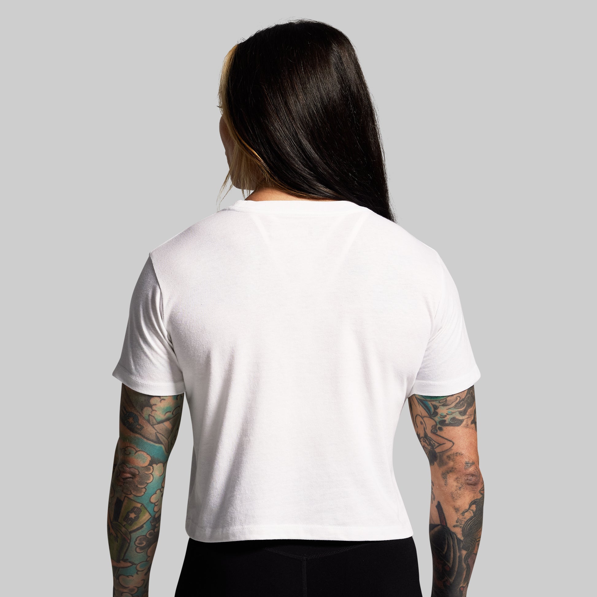 Person wearing a plain white t-shirt on a gray background