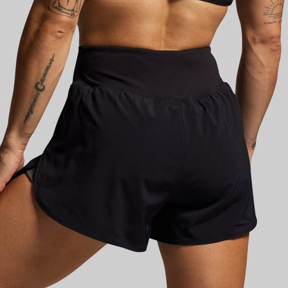 Person wearing black athletic shorts on a plain background