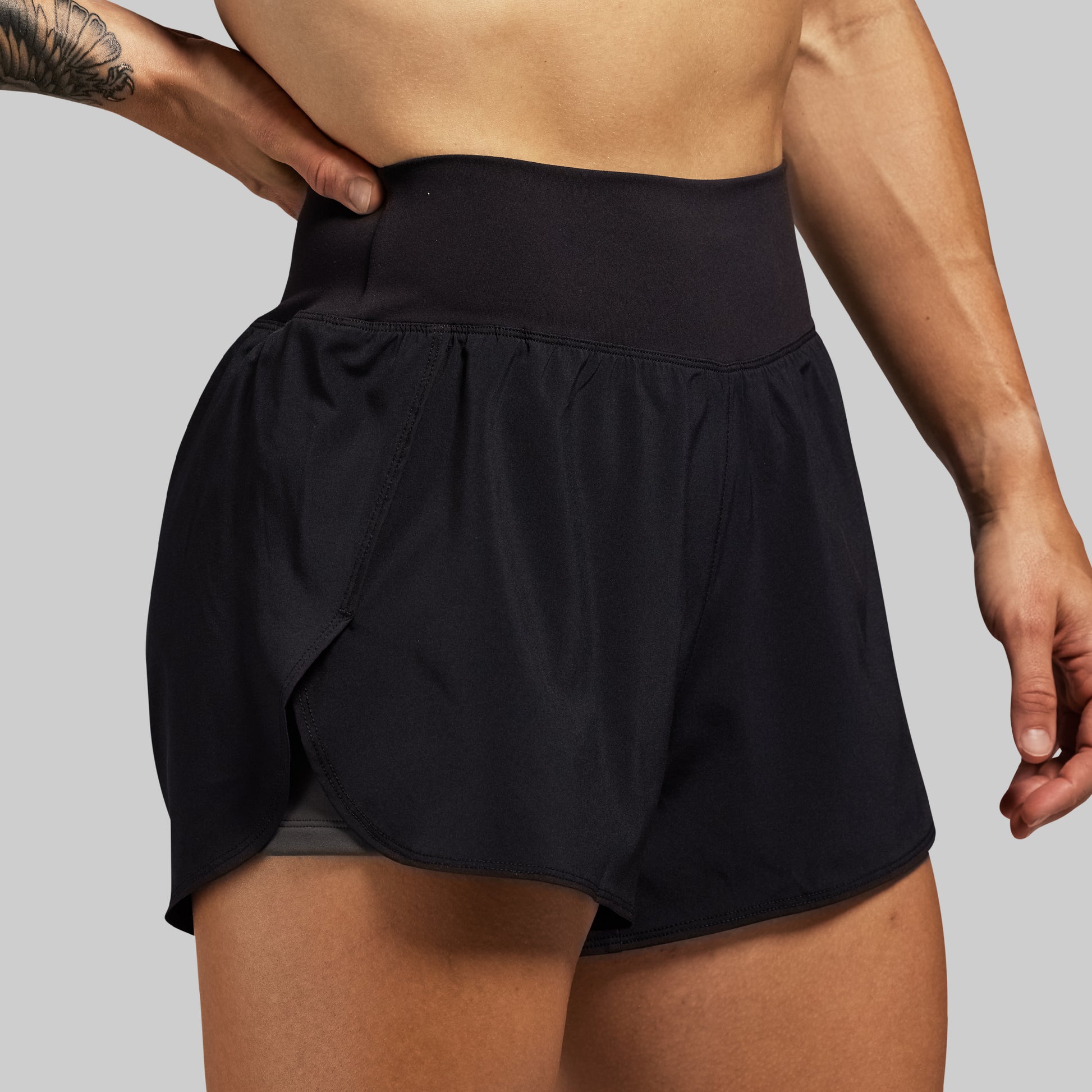 Black athletic shorts worn by a person on a gray background