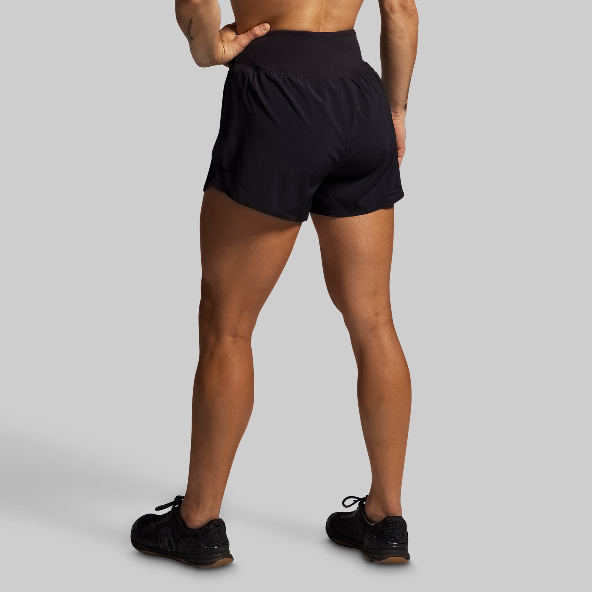 Person wearing black athletic shorts on a gray background