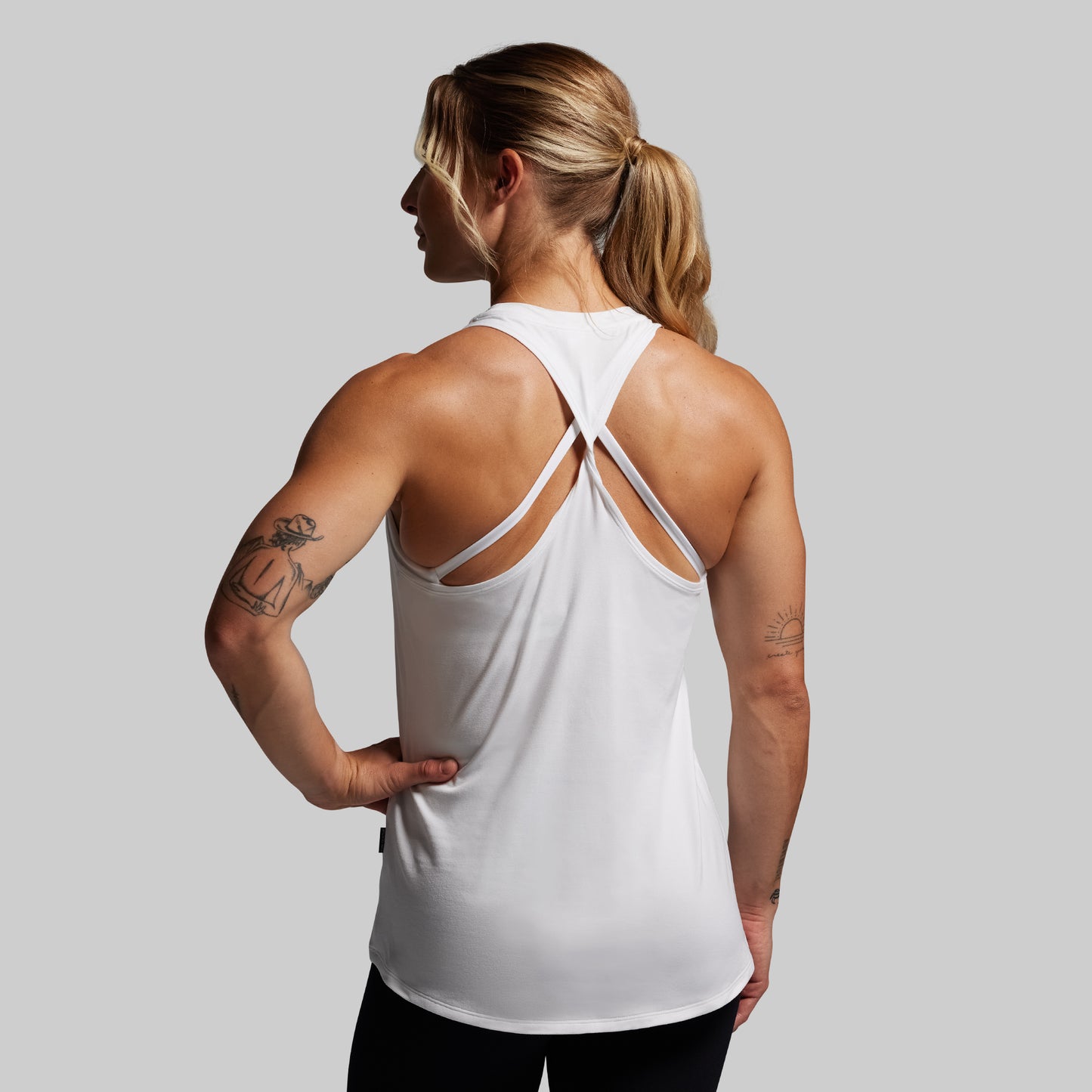 Person wearing a white tank top with thin straps on a plain background