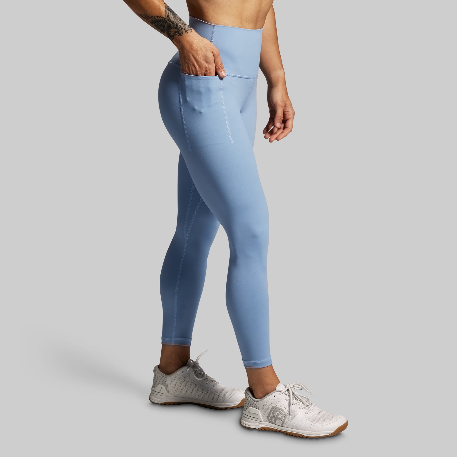 Person wearing light blue leggings on a gray background