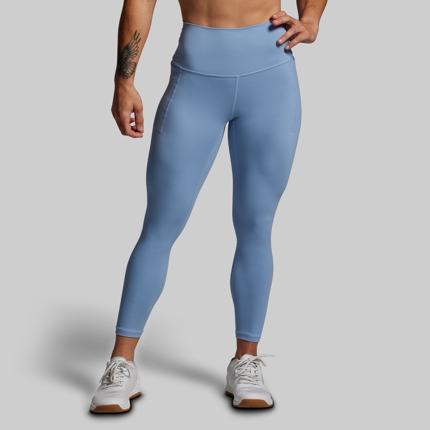 Person wearing light blue leggings on a gray background