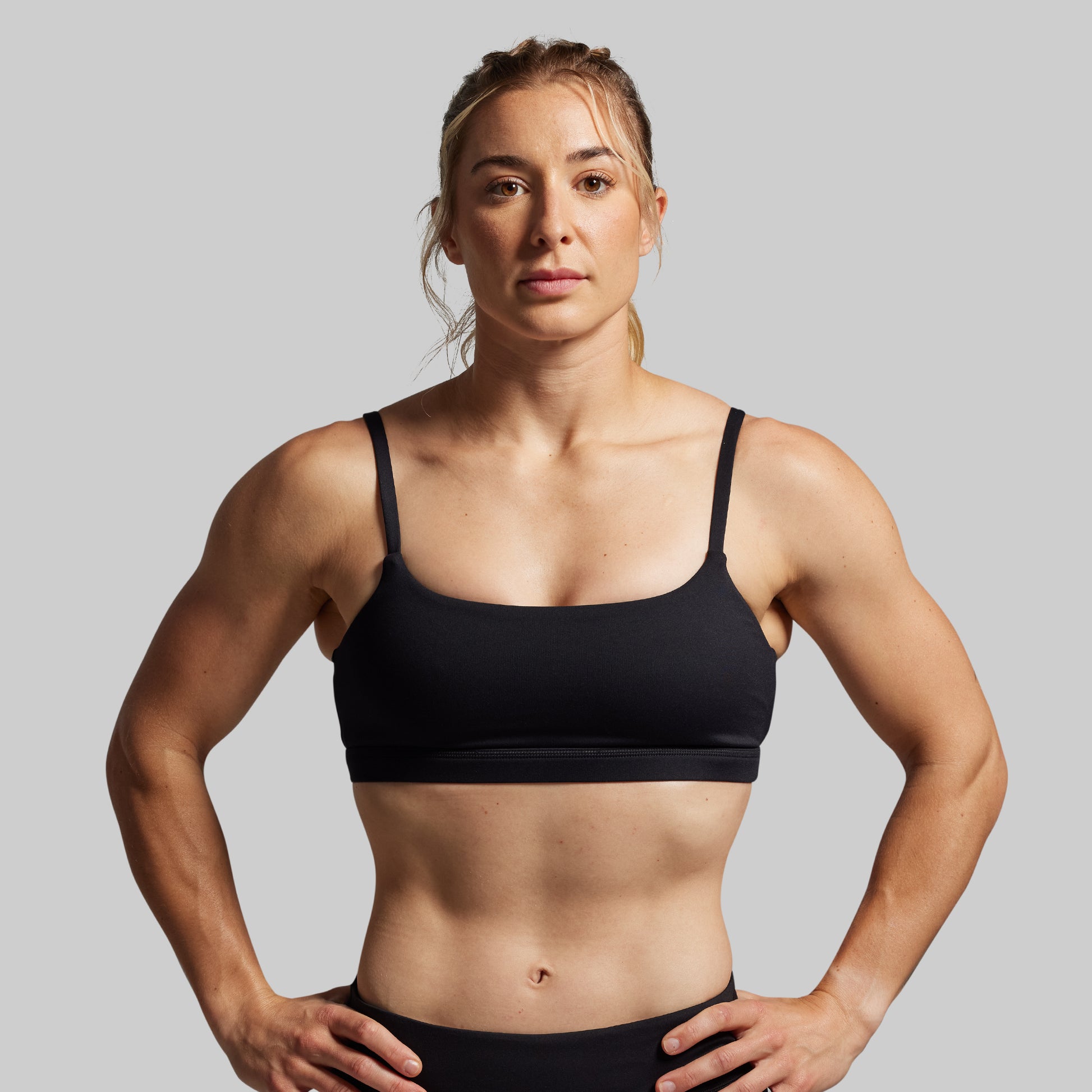 Woman wearing a black sports bra against a gray background