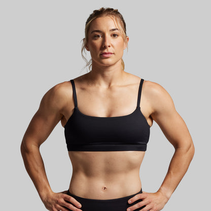 Woman wearing a black sports bra against a gray background