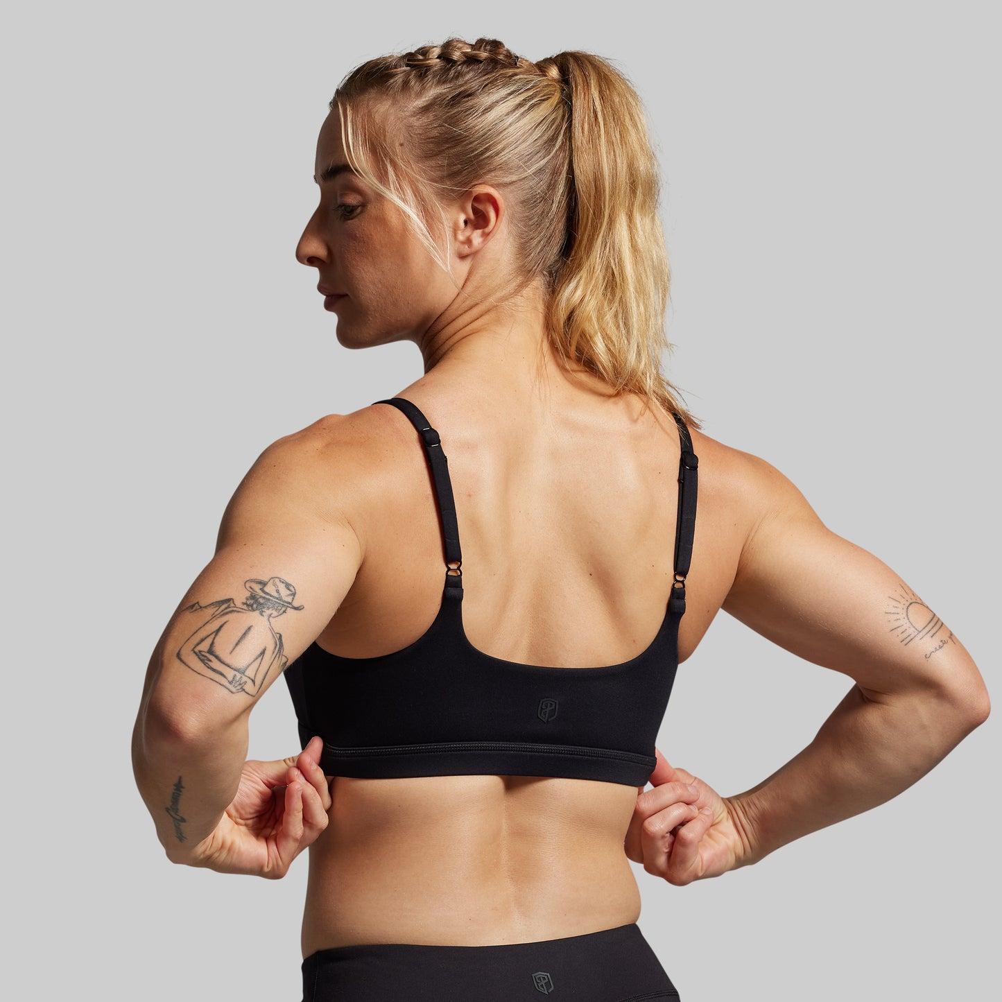 A person wearing a black sports bra with adjustable straps, viewed from the back.
