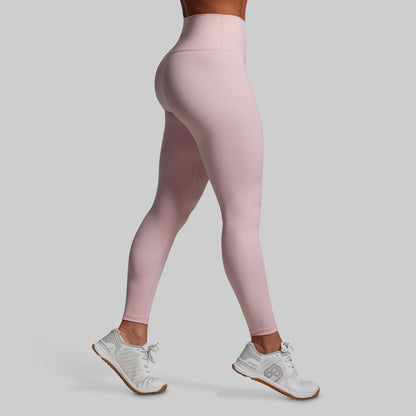 Person wearing pink leggings and white sneakers on a light gray background