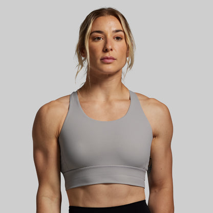 Woman wearing a gray sports bra against a plain background