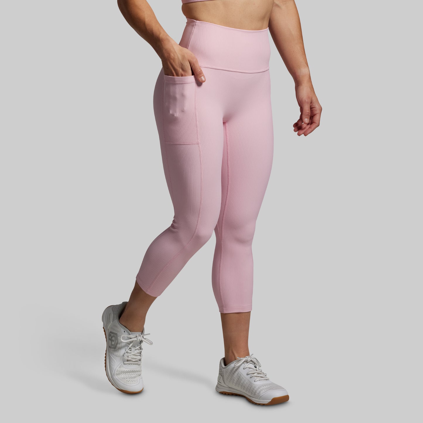 Person wearing pink leggings and white sneakers on a gray background