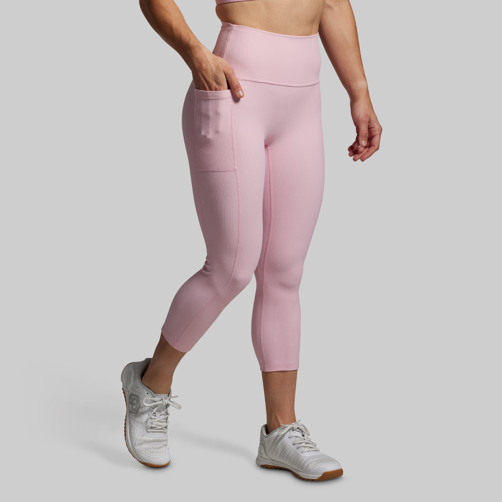 Person wearing pink leggings and white sneakers on a gray background