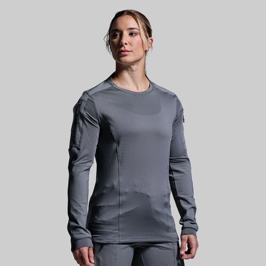Person wearing a gray long-sleeve tactical shirt on a light gray background