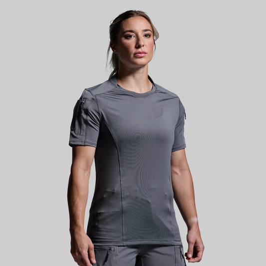 Woman wearing a gray tactical short-sleeve shirt on a plain background