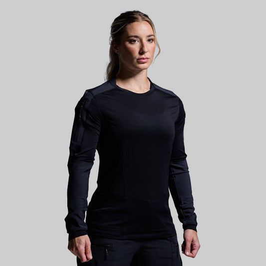 Woman wearing a black long-sleeve top against a gray background