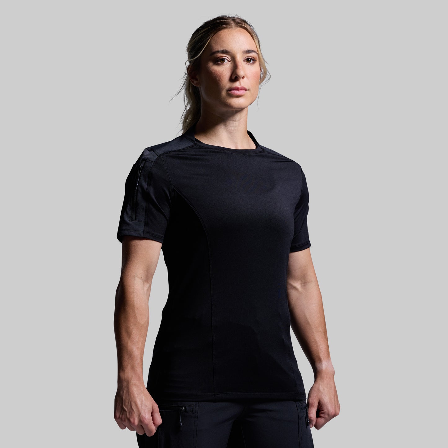 Person wearing a black tactical outfit on a gray background
