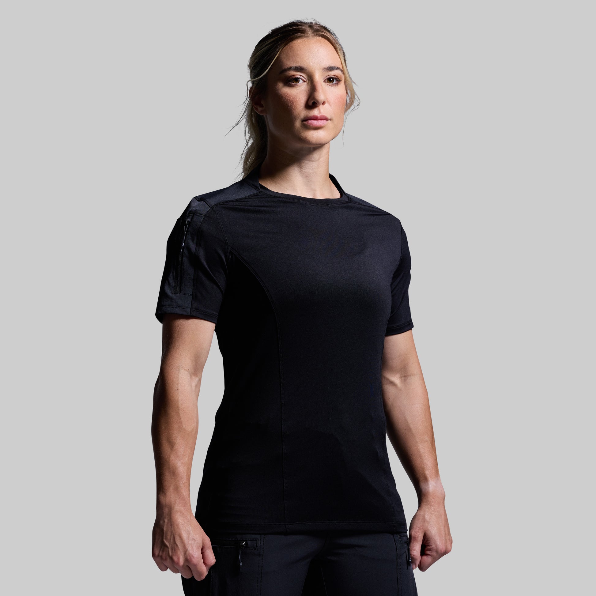 Person wearing a black tactical outfit on a gray background