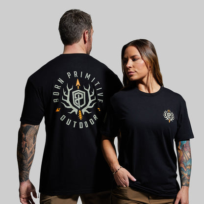 Two people wearing black t-shirts with logos on a gray background